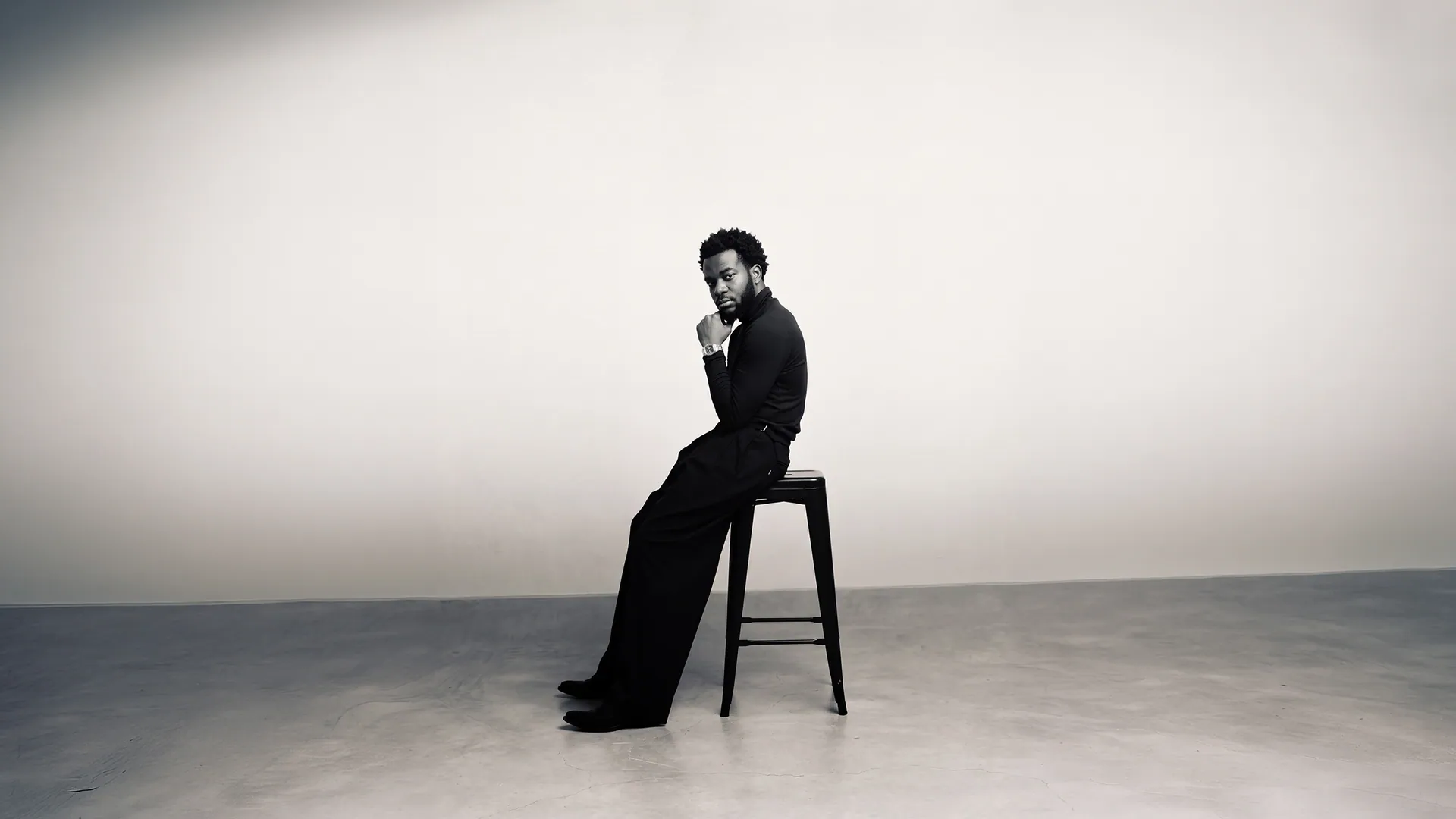 Oluwasegun Elijah Ajanaku seated on a stool in a white studio